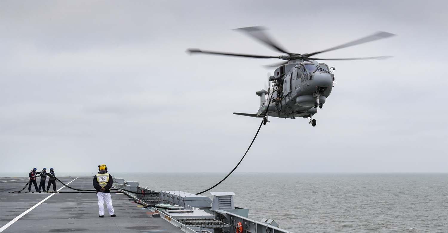 A Merlin from 824 Squadron practices refuelling by hovering just above HMS Queen Elizabeth's flight deck. HMS Queen Elizabeth sailed from Portsmouth on January 24 for a shakedown and training period in UK waters. Picture: Belinda Alker/Royal Navy