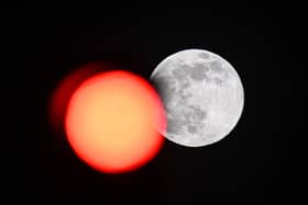 TOPSHOT - This picture taken on February 5, 2023 shows the full moon rising behind a red crossing light in Paris. (Photo by Stefano RELLANDINI / AFP) (Photo by STEFANO RELLANDINI/AFP via Getty Images)