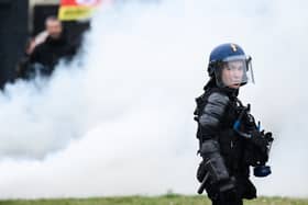 A French gendarme stands next to smoke during a demonstration as part of a national day of strikes and protests, a week after the French government pushed a pensions reform through parliament without a vote, using the article 49.3 of the constitution, in Nantes, western France, on March 23, 2023