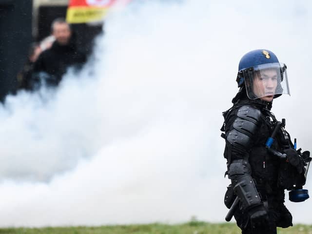 A French gendarme stands next to smoke during a demonstration as part of a national day of strikes and protests, a week after the French government pushed a pensions reform through parliament without a vote, using the article 49.3 of the constitution, in Nantes, western France, on March 23, 2023