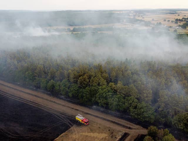 In this aerial view, a fire engine is seen on the field while smoke rises from the trees on July 19, 2022 in Blidworth, England