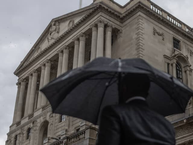 A commuter walks through heavy rain near the Bank of England, London.