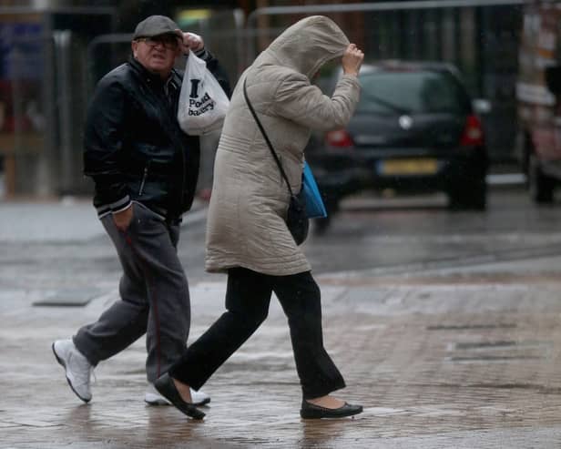 People walk in rain and high winds.