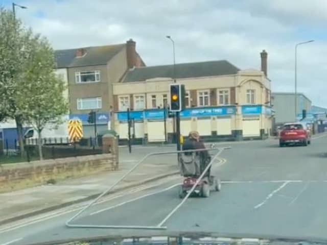 A man tows a metal fence from his mobility scooter in Grimsby. The man was spotted dragging the fence along as he stopped at traffic lights.