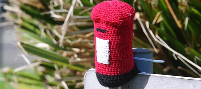 A temporary knitted post box sits at the location where the new post box will be installed. A site suggested to the Royal Mail by Maria.