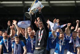 Pompey boss John Mousinho holds the League One trophy aloft. Pic: PA