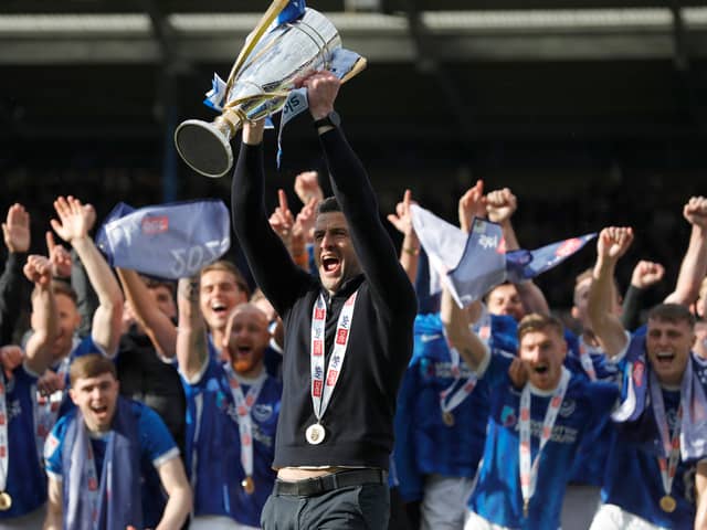 Pompey boss John Mousinho holds the League One trophy aloft. Pic: PA