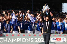 Pompey boss John Mousinho holds aloft the League One championship trophy in front of the Pompey players