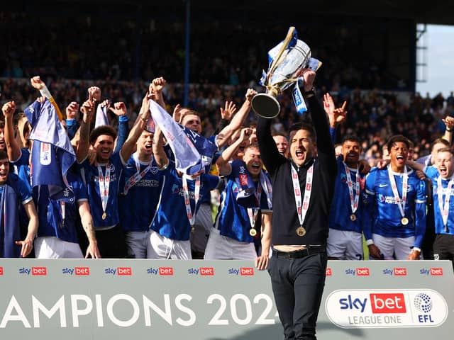 Pompey boss John Mousinho holds aloft the League One championship trophy in front of the Pompey players