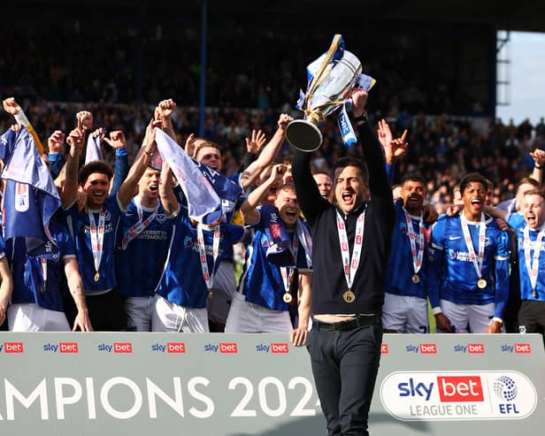 Pompey boss John Mousinho holds aloft the League One championship trophy in front of the Pompey players