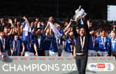 Pompey boss John Mousinho holds aloft the League One championship trophy in front of the Pompey players