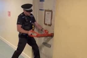 A police officer breaking the door of a flat in Blake Court, South Street, Gosport, where suspected Class C drugs were seized during a warrant. Picture: Gosport Police.