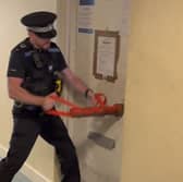 A police officer breaking the door of a flat in Blake Court, South Street, Gosport, where suspected Class C drugs were seized during a warrant. Picture: Gosport Police.