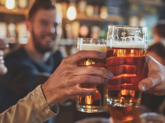 Friends drinking pints and toasting beer at a pub. Image: Sasint/stock.adobe