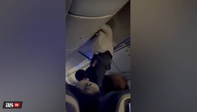 Passengers help man from overhead bin after 'strong turbulence'.