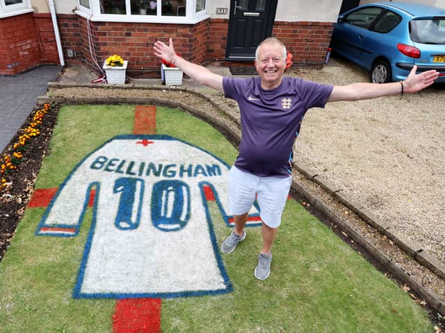 Bryn Nicholls stands next to the Jude Bellingham England shirt mural he has created in his front garden.