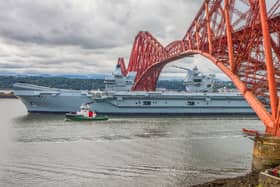 HMS Queen Elizabeth passes under the Forth Bridge as she heads back to sea following lengthy time at Rosyth for repairs and upgrades due to mechanical fault. July 22, 2024.