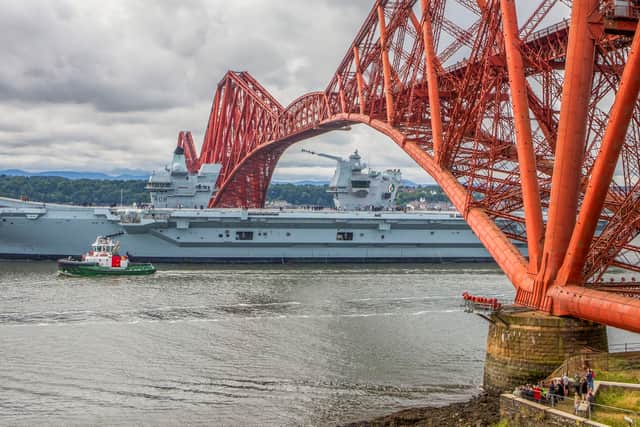 HMS Queen Elizabeth passes under the Forth Bridge as she heads back to sea following lengthy time at Rosyth for repairs and upgrades due to mechanical fault. July 22, 2024.