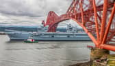 HMS Queen Elizabeth passes under the Forth Bridge as she heads back to sea following lengthy time at Rosyth for repairs and upgrades due to mechanical fault. July 22, 2024.