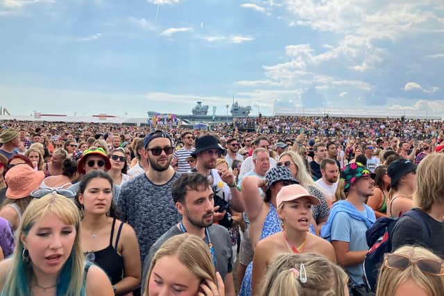 HMS Prince of Wales sailing past Southsea Common in 2022 while the Sugababes perform a special set for the crowd at Victorious Festival.