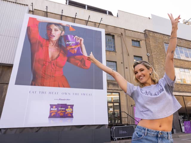 Ashley puts sweat shame to sweat fame by standing in front of her sweating billboard as the new face of Extra Flamin' Hot snacks
