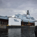 HMS Cardiff being transported on a barge along the River Clyde, before slowly being lowered into the water.