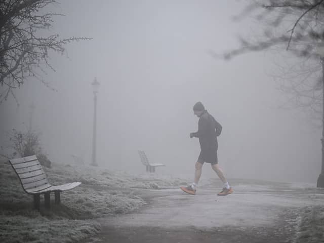 A jogger makes their way through fog on a frosty morning.