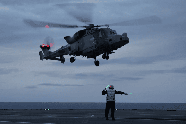 A pilot stationed on HMS Queen Elizabeth saved six lives after carrying out an emergency landing during a medical evacuation.