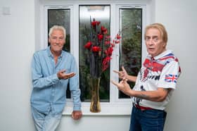 Residents Ian Hunter (L) and Thomas Dunn (R) standing in their hallway next to a vase of flowers.