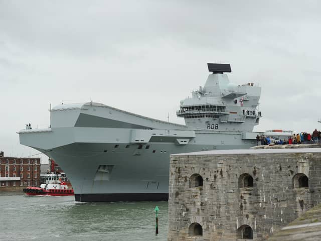 HMS Queen Elizabeth leaving Portsmouth on October 21, 2024, as crowds gather at The Round Tower in Old Portsmouth and along The Hot Walls to watch the aircraft carrier leave.