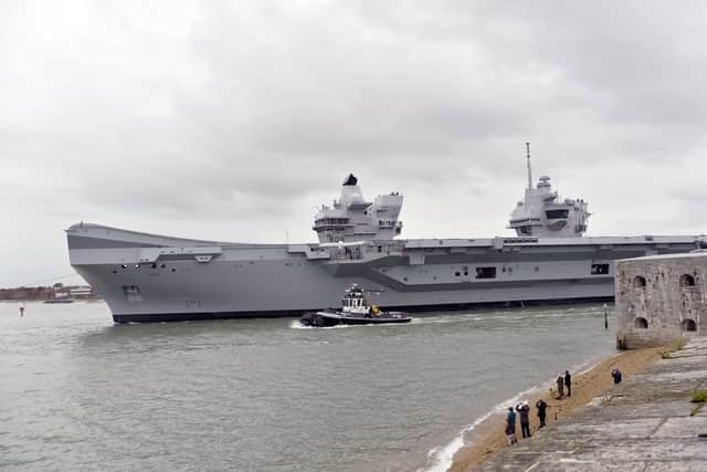 HMS Queen Elizabeth leaving Portsmouth on October 21, 2024, as crowds gather at The Round Tower in Old Portsmouth and along The Hot Walls to watch the aircraft carrier leave.