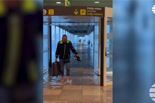 Passenger wades through flood water at Barcelona's El Prat airport.