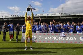 Keeper Will Norris holds aloft the League One championship trophy in front of his team-mates at Fratton Park