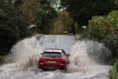 Car drives along flooded road.