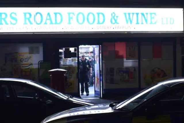 Police coming out of Somers Road store on Saturday after stabbing
