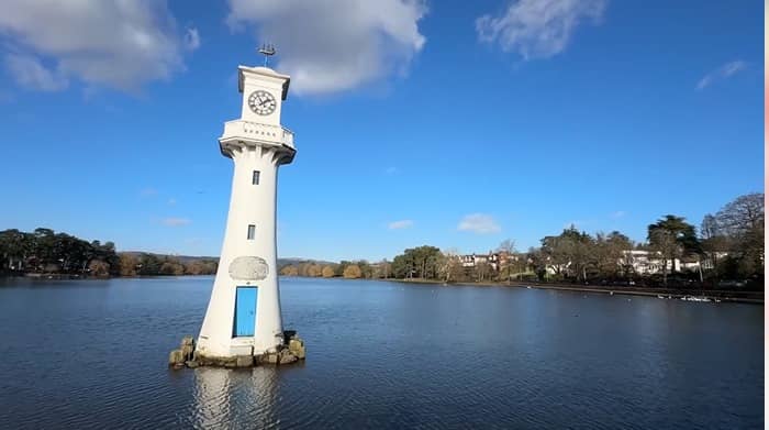 A white clock tower surrounded by water in a serene location