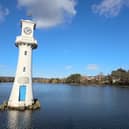 A white clock tower surrounded by water in a serene location