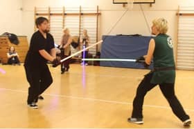 Two people, training with lightsabers