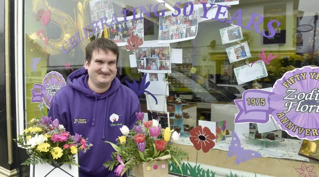 Adam Ayling, owner of Zodiac Florist, with the window display of memories to celebrate the shop's 50 year anniversary.