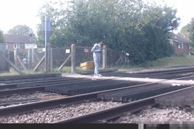 Teen stares at phone while stood on level crossing. Network Rail 