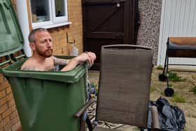 Martin Lynch taking a cold water bath in his wheelie bin