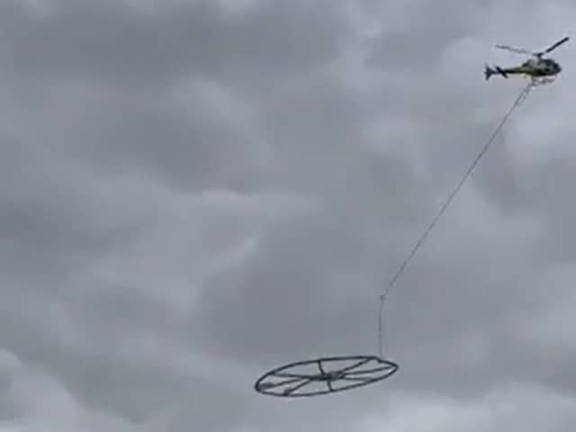 Helicopter carrying large metal circle.