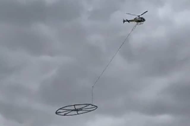 Helicopter carrying large metal circle.