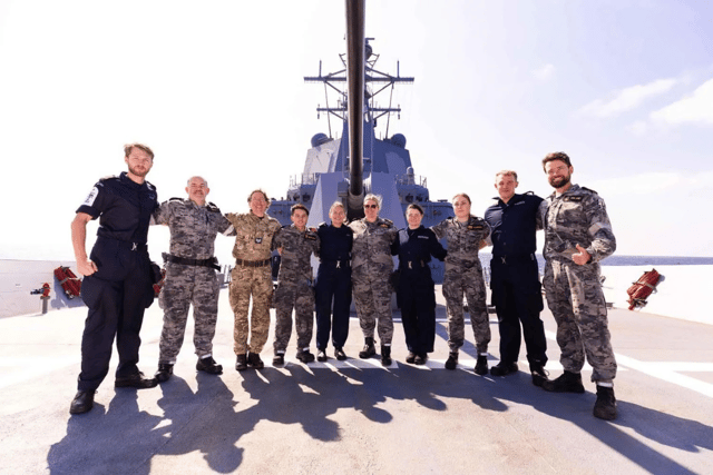 HMS Spey's crew pose with Australian comrades under the barrel of HMAS Sydney's 5in gun.