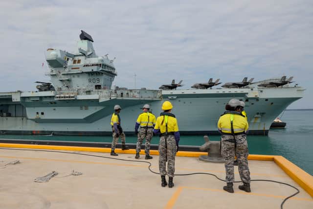 The government has issued a notice calling for stealth combat drones to be added to HMS Prince of Wales and HMS Queen Elizabeth, boosting the Royal Navy and RAF. Pictured: Members of Port Services - North wait for the arrival of the HMS Prince of Wales alongside Kuru Wharf at HMAS Coonawarra, Darwin, Northern Territory, Australia.