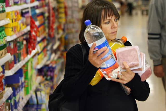 A woman carries her shopping at a branch of Tesco. Essentials like vegetables, milk, eggs, cheese, and fish are driving higher household costs. (Photo: ADRIAN DENNIS/AFP via Getty Images)
