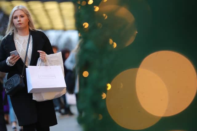A shopper walks with her purchases along the main shopping street Oxford Street in London. Starting to save in September gives you three months to build a festive fund (Photo by DANIEL LEAL/AFP via Getty Images)