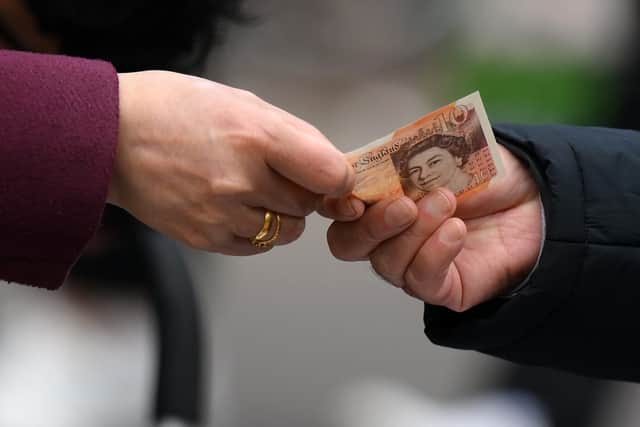 A customer pays for goods at a market in east London. Millions on long-term benefits will receive a £10 Christmas Bonus from the DWP this December (Photo: DANIEL LEAL/AFP via Getty Images)