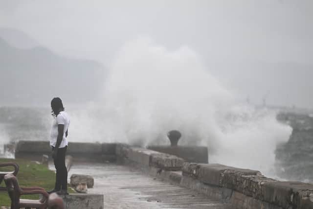 A man watches the waves crash into the walls at the Kingston Waterfront on October 27, 2025. Hurricane Melissa threatened Jamaica with potentially deadly rains after rapidly intensifying into a top-level Category 5 storm, as residents scrambled for shelter from what could be the island's most violent weather on record. The government has confirmed that British Royal Navy and military assets will be on hand to assist with disaster relief.