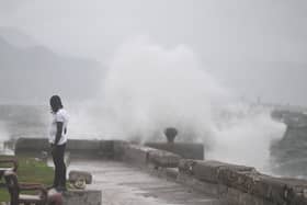 A man watches the waves crash into the walls at the Kingston Waterfront on October 27, 2025. Hurricane Melissa threatened Jamaica with potentially deadly rains after rapidly intensifying into a top-level Category 5 storm, as residents scrambled for shelter from what could be the island's most violent weather on record. The government has confirmed that British Royal Navy and military assets will be on hand to assist with disaster relief.